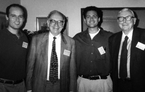 A black and white poto of Warren Buffet standing with three other men.