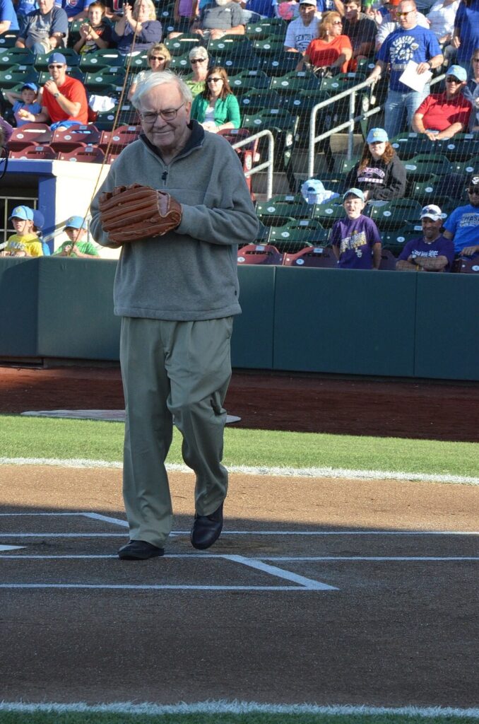 Warren Buffet in a baseball field participating during a game.