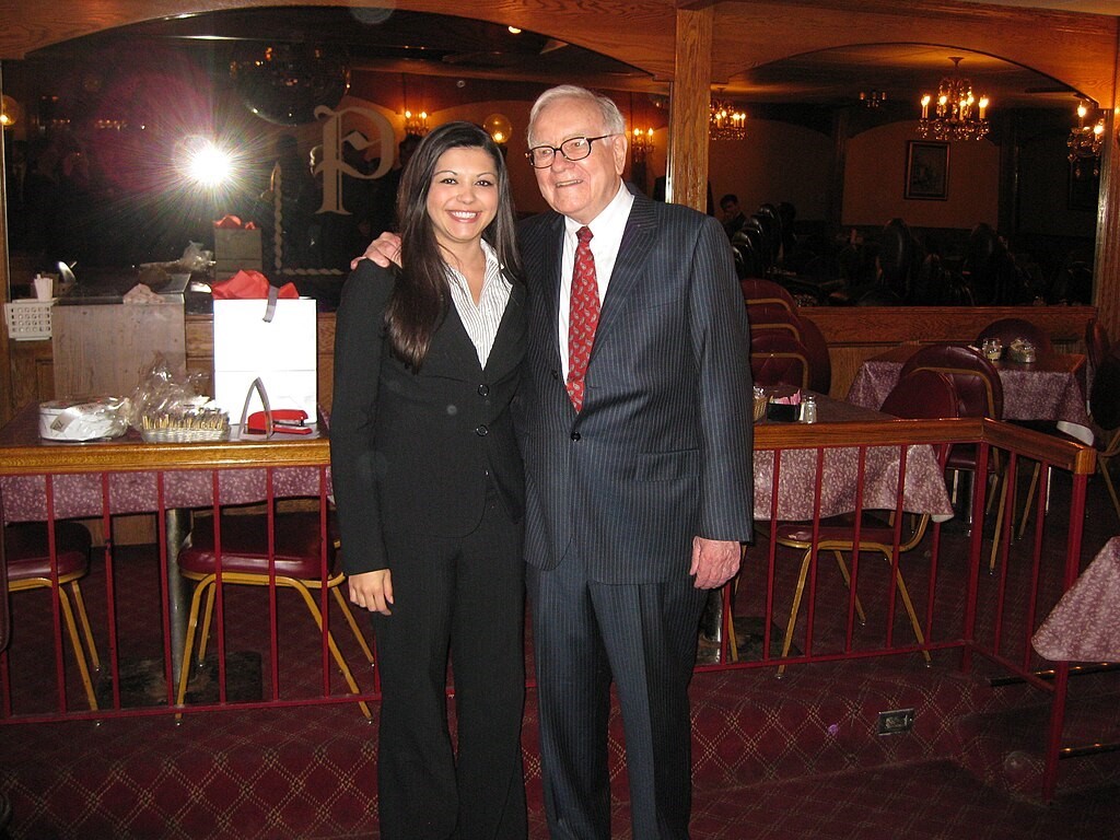 Warren Buffet at a shareholders meeting posing with a female participant.