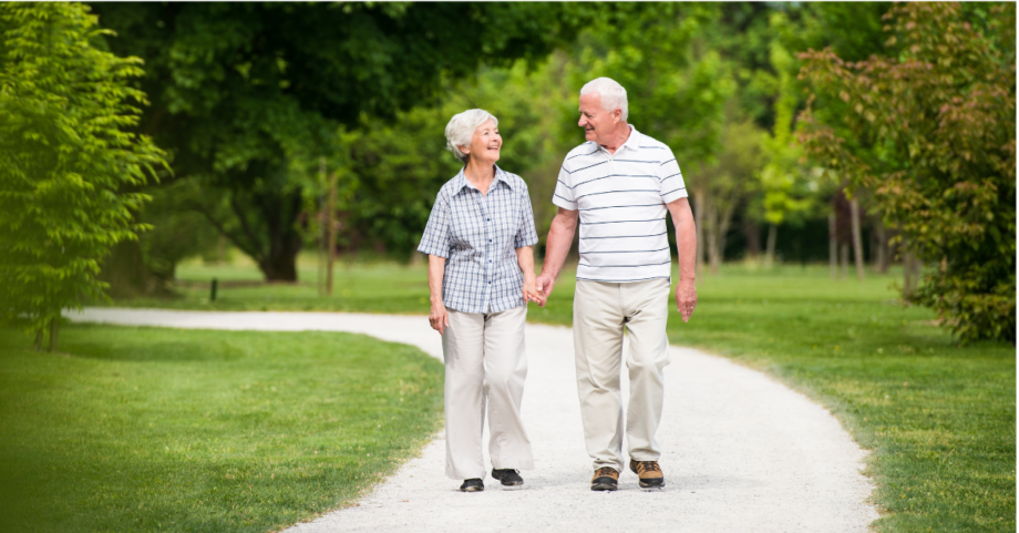 Senior couple walking together on a park path, representing healthy aging, balance, and bone support.