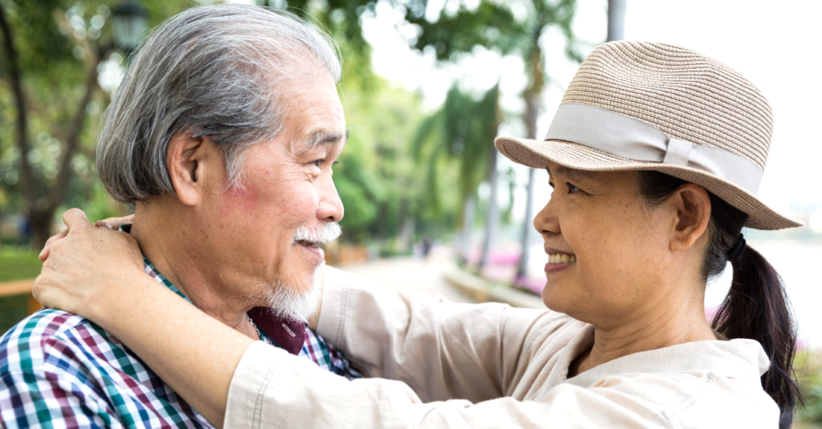 Senior couple embracing and smiling at each other outdoors, representing intimacy and emotional connection in healthy aging.